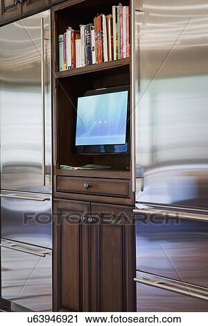 Stock Image - Television between two stainless steel refrigerators; Irvine; California; USA. Fotosearch