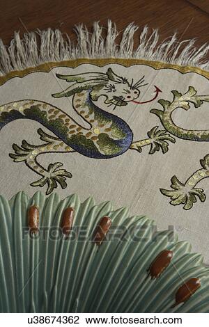 Stock Image - TEXTILES: ANTIQUE embroidered dragon on linen, cattail plate, Arts and Crafts. Fotosearch