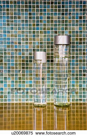 Stock Photography - Two jars of water on countertop in front of mosaic tile backsplash; Ontario; California; USA. Fotosearch