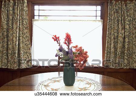 Stock Photo - Vase filled with flowers on a dining room table; San Diego; California; USA. Fotosearch