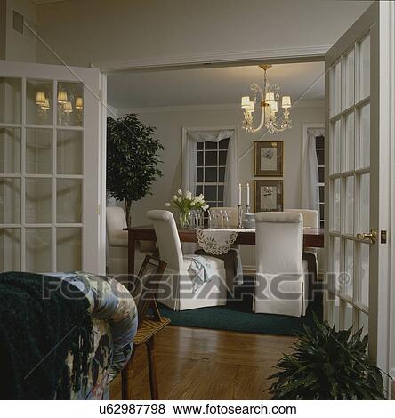 Stock Photo - View of dining area through open French doors in traditional house. Fotosearch