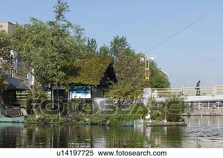 Stock Photography - View of floating cottage with plants by footbridge. Fotosearch