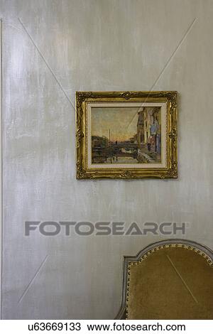 Stock Image - WALL TREATMENTS: special Amour coat plaster paint, iridescent pale blues and silver, part of chair in right corner, gold framed picture on wall. Fotosearch