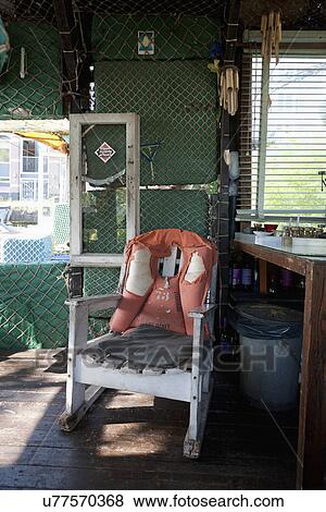 Weathered life jacket on wooden armchair by table View Large Photo Image Stock Photo - Weathered life jacket on wooden armchair by table. Fotosearch