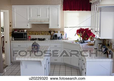 Stock Image - White monochromatic traditional kitchen with island, Laguna Beach, California, USA. Fotosearch
