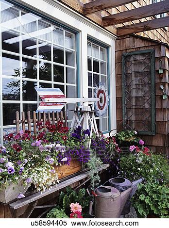Window boxes: over flowing with flowers, sits on vintage luggage rack under window. Window whirligig, potted plants, tin watering cans. View Large Photo Image Stock Photography - Window boxes: over flowing with flowers, sits on vintage luggage rack under window. Window whirligig, potted plants, tin watering cans.. Fotosearch