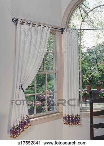 Stock Image - Window with decorative curtains in traditional home.. Fotosearch