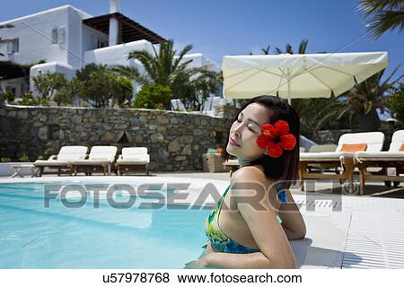 Stock Photo - Woman relaxing in swimming pool, Mykonos, Greece. Fotosearch