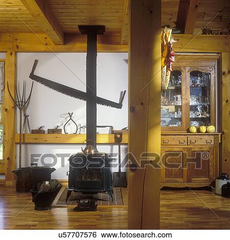 WOOD BURNING STOVES: Auxiliary heat in Living Room, antique tools on display, antique cupboard. Oak flooring, pine posts and beams. View Large Photo Image Stock Photograph - WOOD BURNING STOVES: Auxiliary heat in Living Room, antique tools on display, antique cupboard. Oak flooring, pine posts and beams. . Fotosearch