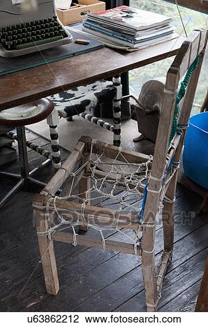 Stock Image - Wooden chair made of commercial fishing nets and typewriter on table. Fotosearch