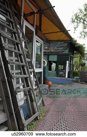 Stock Photo - Wooden ladders in front of house with commercial fishing nets floor. Fotosearch