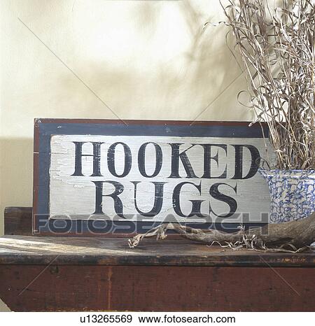 Wooden painted sign 'Hooked rugs' and dried grass in spongeware vase on wooden table top View Large Photo Image Stock Photo - Wooden painted sign 'Hooked rugs' and dried grass in spongeware vase on wooden table top. Fotosearch
