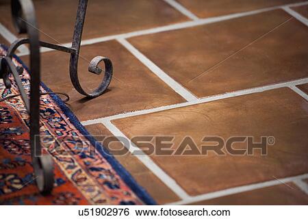 Stock Photograph - Wrought iron base of lamp on terracotta tile floor; Irvine; California; USA. Fotosearch