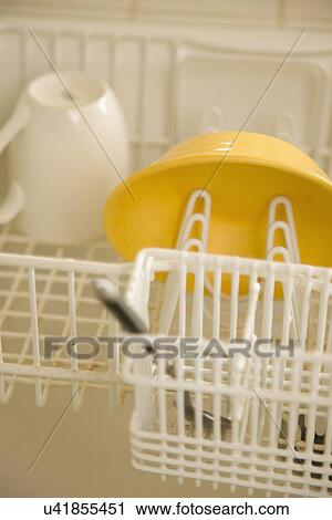 Stock Image - Yellow bowl in dish drying rack; Carpinteria; California; USA. Fotosearch
