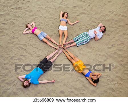 Aerial view of friends lying in star shape on sand View Large Photo Image Stock Photo - Aerial view of friends lying in star shape on sand. Fotosearch