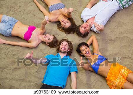 Aerial view of friends lying with heads together on sand View Large Photo Image Stock Photo - Aerial view of friends lying with heads together on sand. Fotosearch