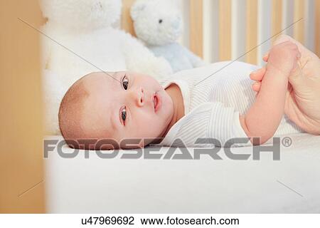 Baby boy in crib holding mothers thumb View Large Photo Image Stock Image - Baby boy in crib holding mothers thumb. Fotosearch