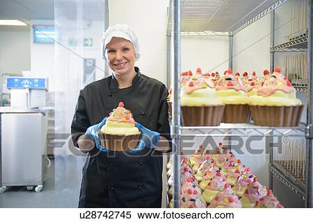 Stock Photography - Chocolatier holding a giant chocolate cupcake. Fotosearch