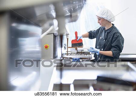 Chocolatier smoothing chocolate in moulds in sweet factory View Large Photo Image Stock Image - Chocolatier smoothing chocolate in moulds in sweet factory. Fotosearch