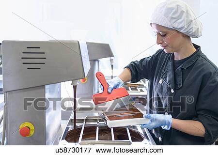 Chocolatier smoothing chocolate in moulds View Large Photo Image Stock Photo - Chocolatier smoothing chocolate in moulds. Fotosearch