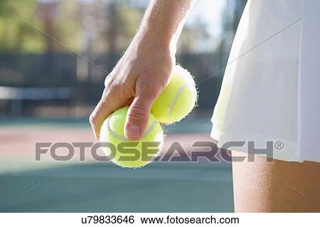 Stock Photograph - Close up of female tennis player holding tennis balls. Fotosearch