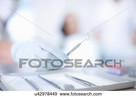 Stock Photo - Close up of hand holding dentist instrument. Fotosearch