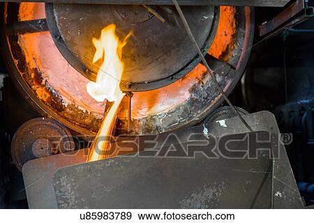 Stock Photo - Close up of machinery and molten metal in steel foundry. Fotosearch