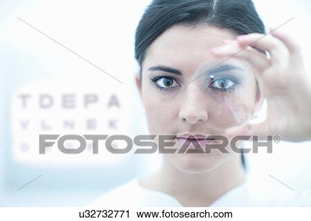 Stock Image - Close up of optician holding lens in eye clinic. Fotosearch