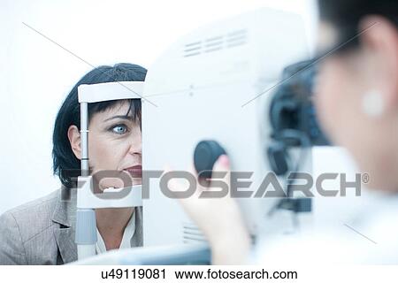 Stock Image - Close up of optician monitoring patient in eye clinic. Fotosearch