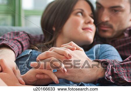 Stock Image - Close up of romantic young couple on sofa. Fotosearch