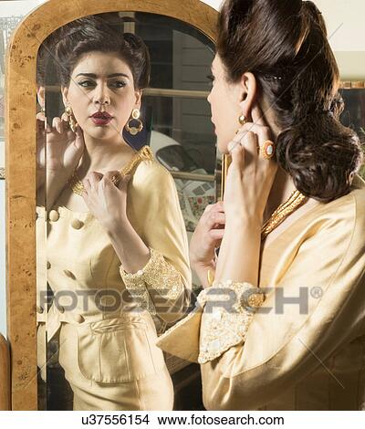 Picture - Close up of woman in vintage clothes looking in mirror. Fotosearch