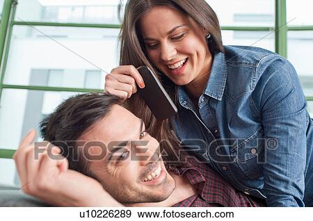Close up of young couple at home messing about with mobile phone View Large Photo Image Stock Photo - Close up of young couple at home messing about with mobile phone. Fotosearch