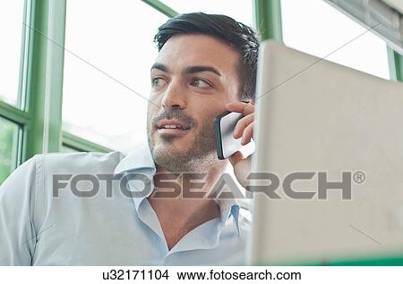 Picture - Close up of young male office worker talking on mobile phone. Fotosearch