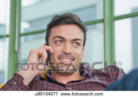 Stock Photo - Close up of young man at home using his mobile phone. Fotosearch