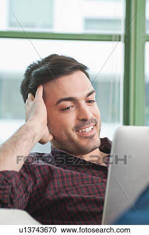 Stock Image - Close up of young man at home using digital tablet. Fotosearch