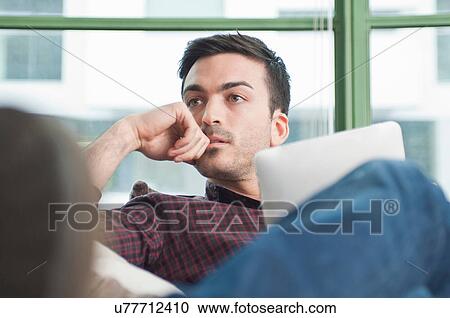 Stock Image - Close up of young man at home with digital tablet. Fotosearch