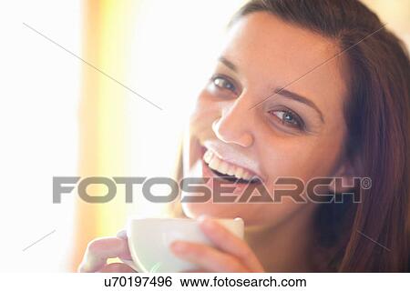 Stock Photograph - Close up of young woman in cafe with foam mustache. Fotosearch
