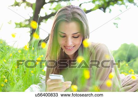 Close up of young woman in field looking at mobile View Large Photo Image Stock Image - Close up of young woman in field looking at mobile. Fotosearch
