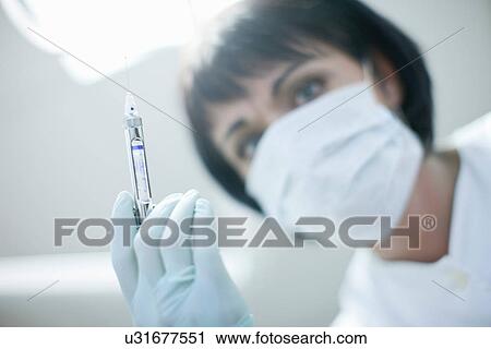 Stock Image - Close up portrait of dentist holding syringe. Fotosearch