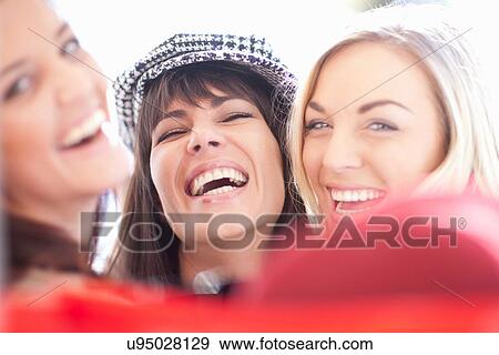 Stock Photo - Close up portrait of three female friends laughing. Fotosearch