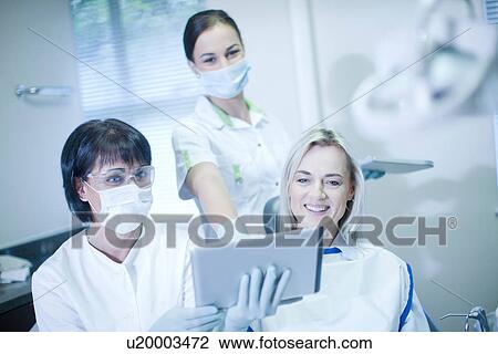 Stock Image - Dentist and patient looking at digital tablet. Fotosearch