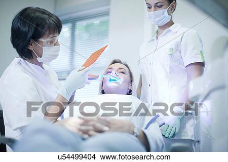 Dentist applying ultraviolet light to patients teeth View Large Photo Image Picture - Dentist applying ultraviolet light to patients teeth. Fotosearch