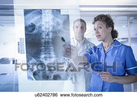 Doctor and nurse looking at xray results displayed on screen View Large Photo Image Stock Photograph - Doctor and nurse looking at xray results displayed on screen. Fotosearch