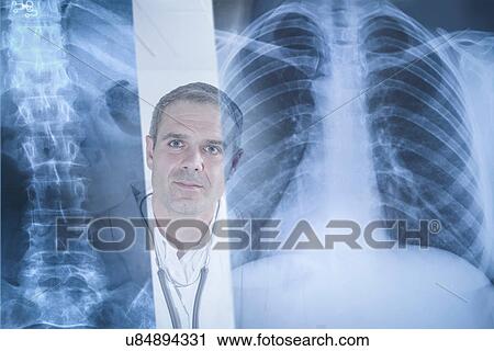 Stock Image - Doctor examining xray results displayed on screen. Fotosearch