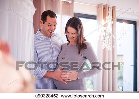 Stock Image - Expectant couple touching baby bump. Fotosearch