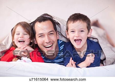 Father and two young children posing under duvet View Large Photo Image Picture - Father and two young children posing under duvet. Fotosearch