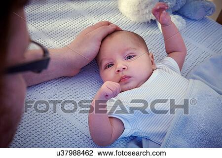 Stock Image - Father consoling baby in crib. Fotosearch