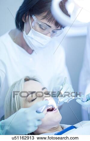Stock Image - Female dentist examining patients teeth. Fotosearch