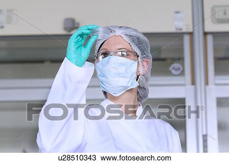 Stock Image - Female scientist examining petri dish. Fotosearch