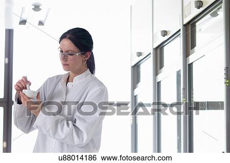 Stock Photograph - Female scientist grinding sample in mortar and pestle. Fotosearch
